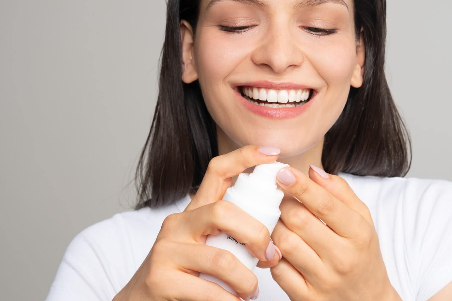 Brünette Frau macht sich Creme auf den Finger