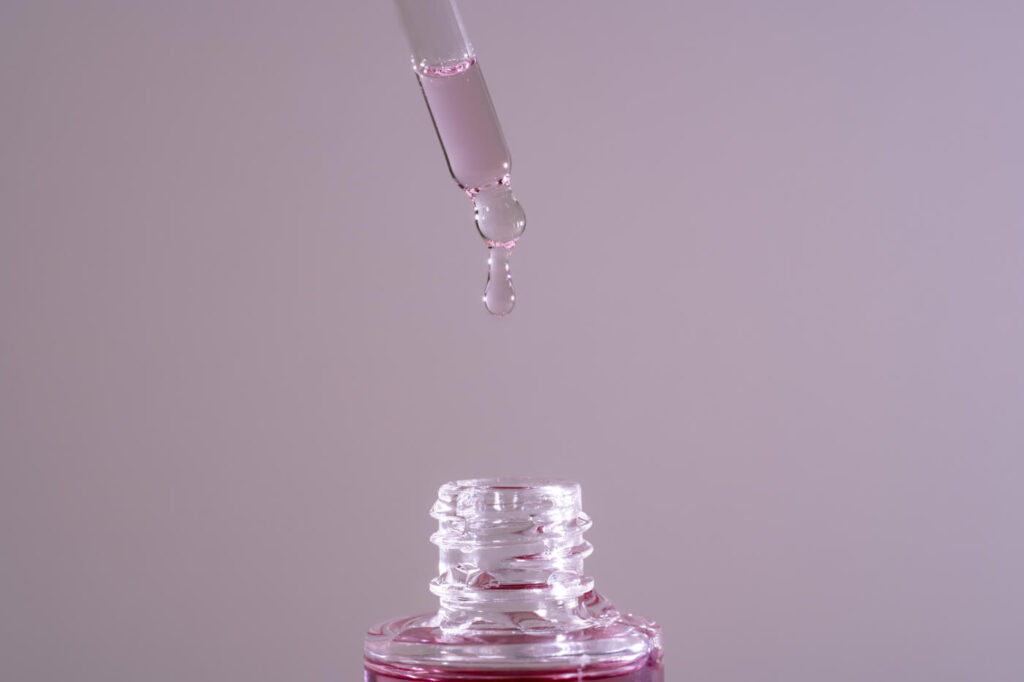 Serum tropft aus Pipette in Glasflasche
