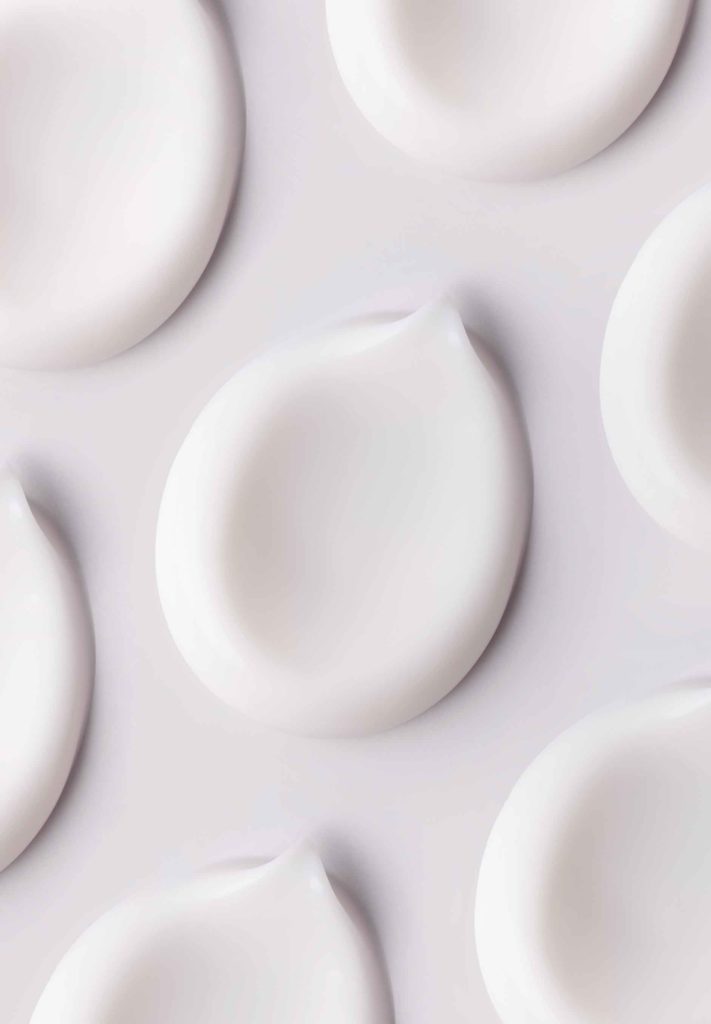 cosmetic smears of creamy texture on gray background